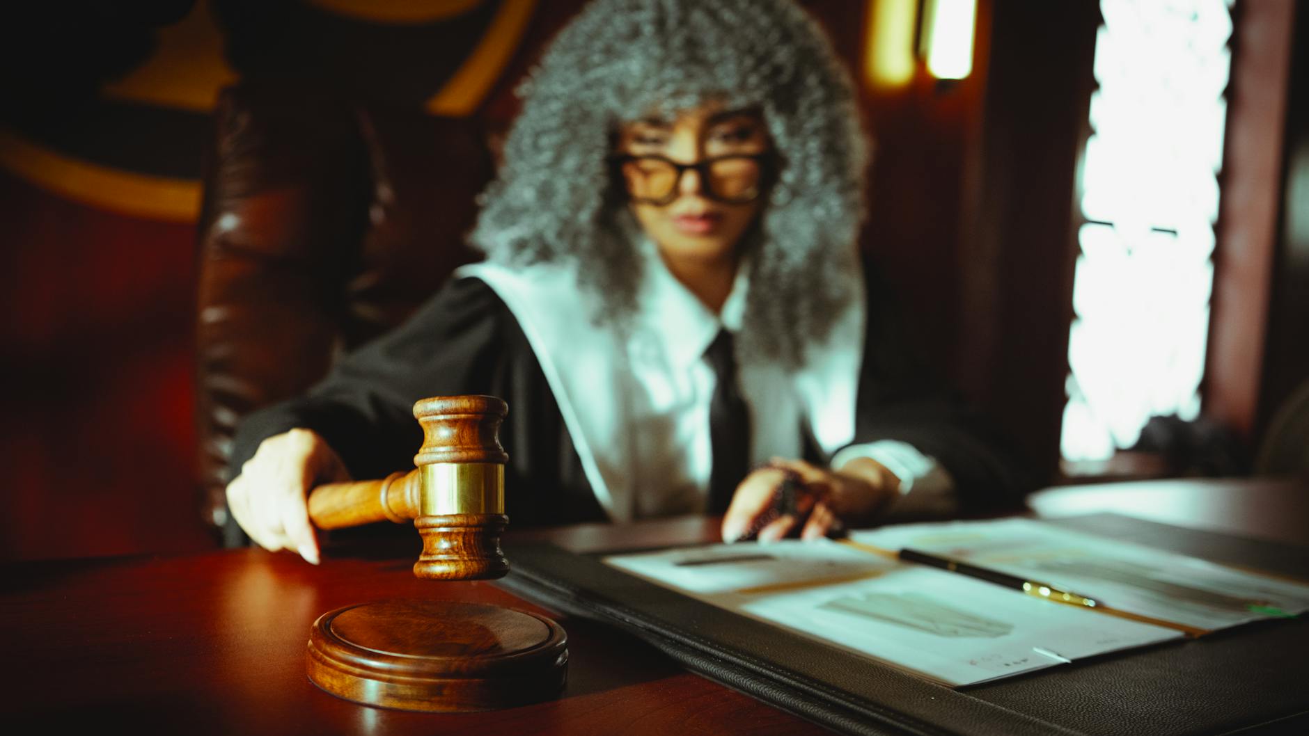 A judge in a courtroom holding a gavel, focused on legal documents.