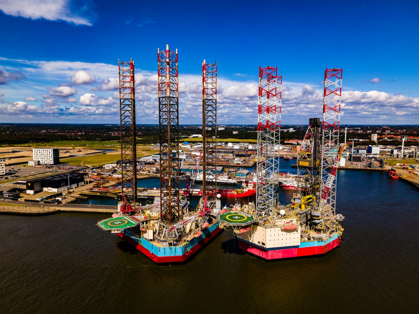 Stunning aerial view of oil rigs docked at the port of Esbjerg in Denmark. Clear day with vibrant colors.