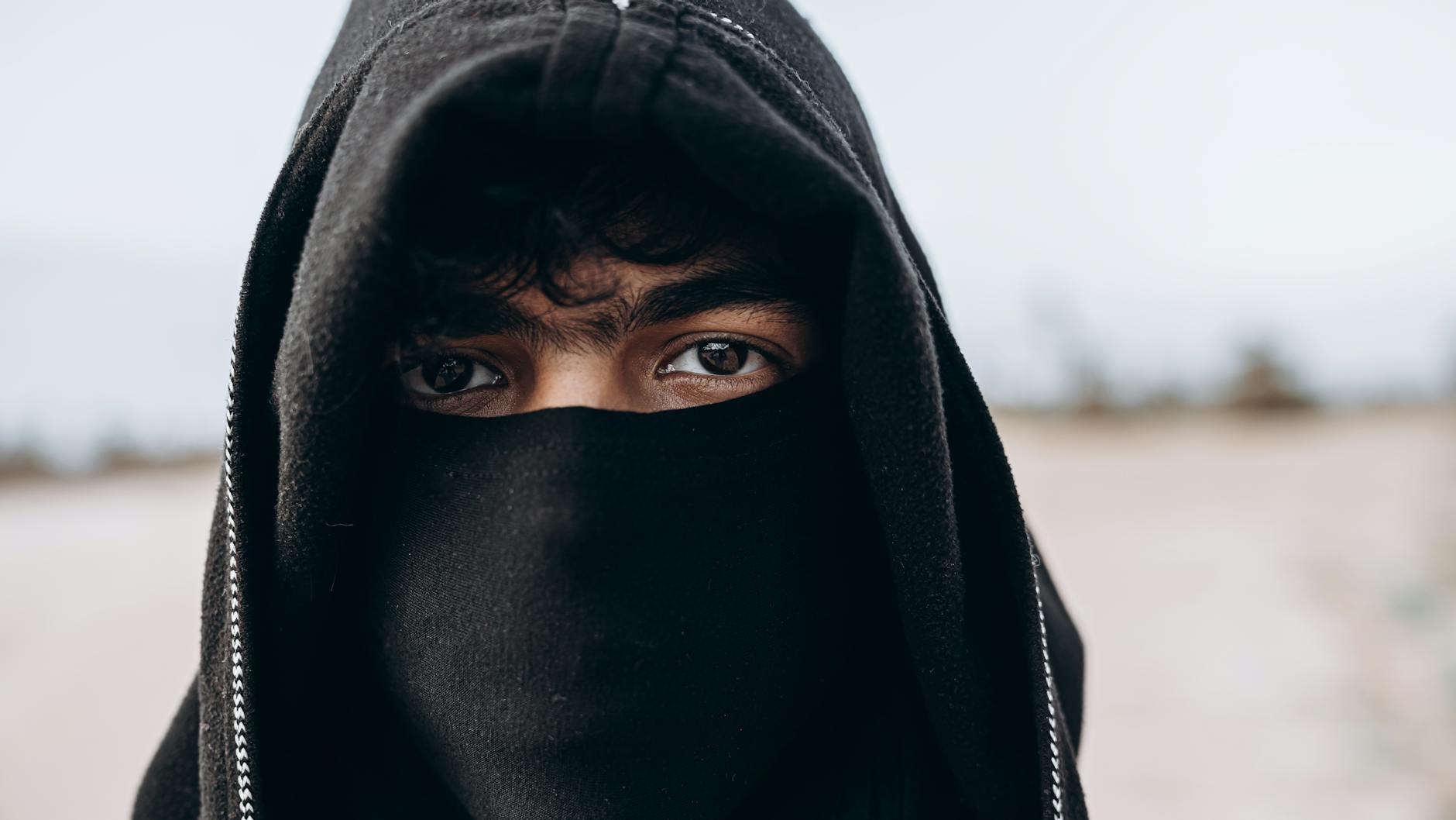 Close-up portrait of a hooded person in the Moroccan desert.