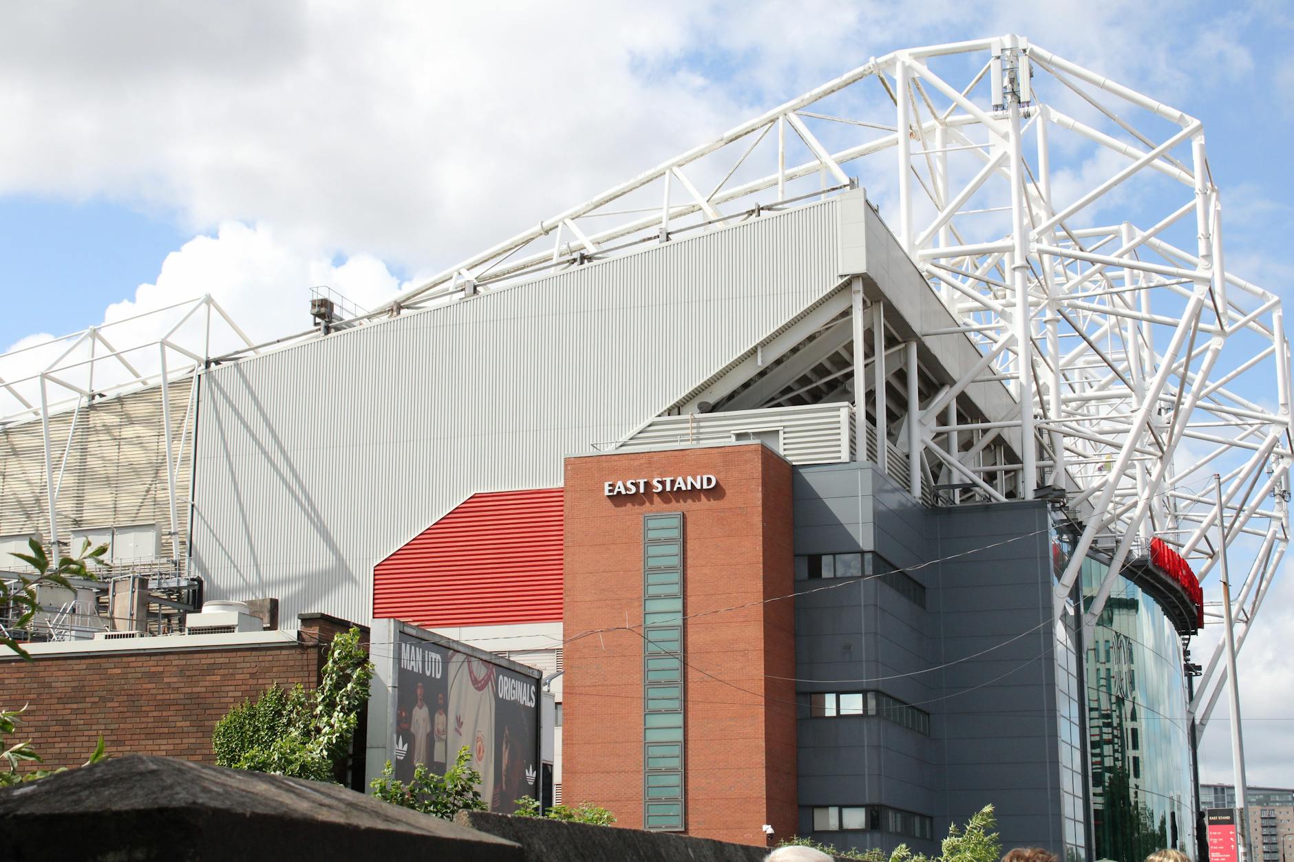 Exterior view of the East Stand at Old Trafford Stadium on a sunny day.